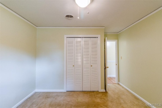 unfurnished bedroom with carpet, crown molding, a closet, visible vents, and baseboards