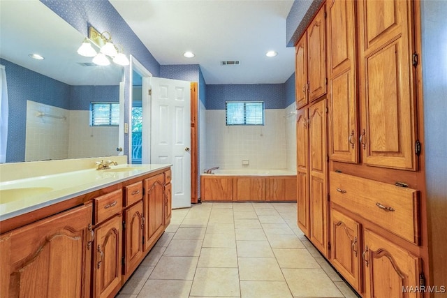 bathroom with double vanity, visible vents, a sink, tile patterned flooring, and a bath