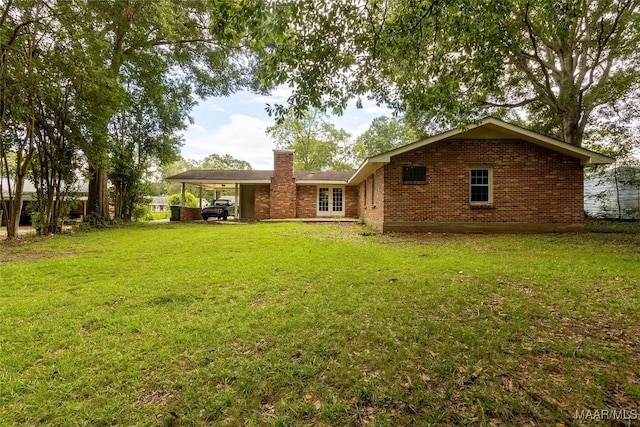 rear view of house featuring a carport, a yard, french doors, and brick siding