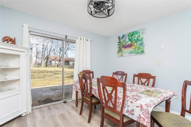 dining area with light wood-type flooring and baseboards