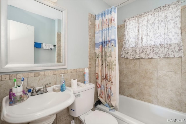 5217 W Shades Valley Dr, Montgomery, AL 36108 - bathroom featuring toilet, a sink, tile walls, wainscoting, and shower / bath combination with curtain