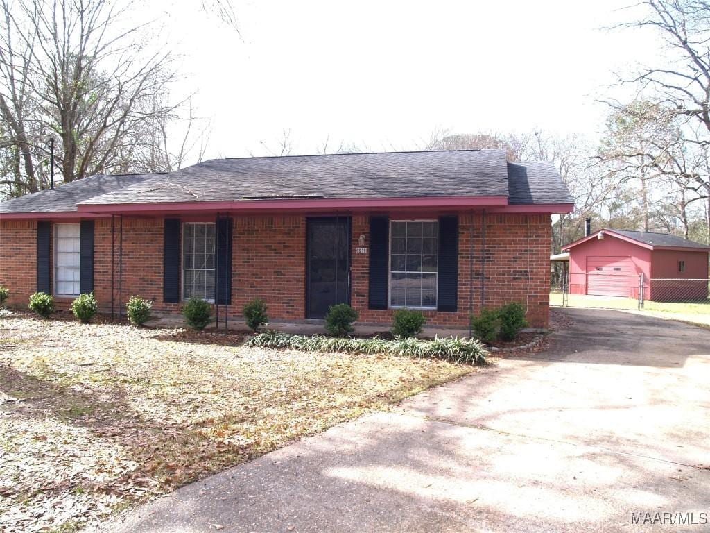 view of front of home with a porch, brick siding, an outdoor structure, and fence