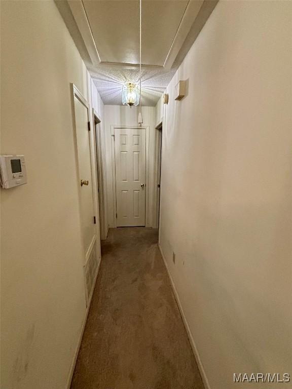 corridor with carpet, attic access, and baseboards