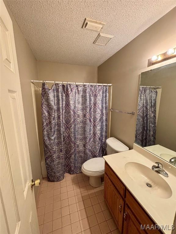 bathroom featuring toilet, a shower with shower curtain, vanity, and tile patterned floors