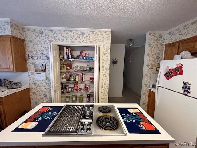 kitchen featuring wallpapered walls, brown cabinets, freestanding refrigerator, light countertops, and a textured ceiling