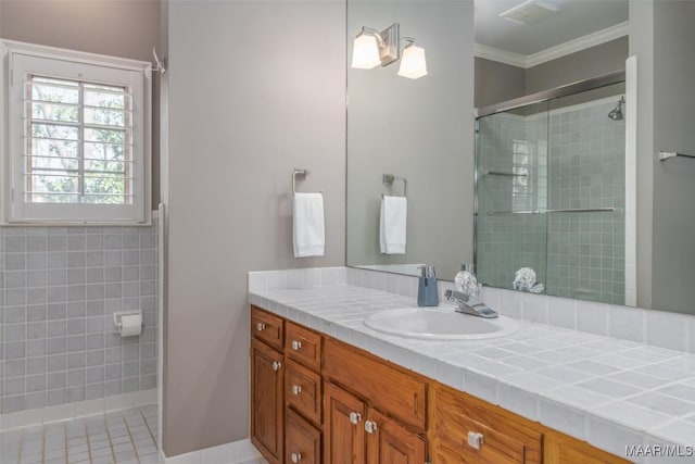 bathroom featuring ornamental molding, a tile shower, and vanity