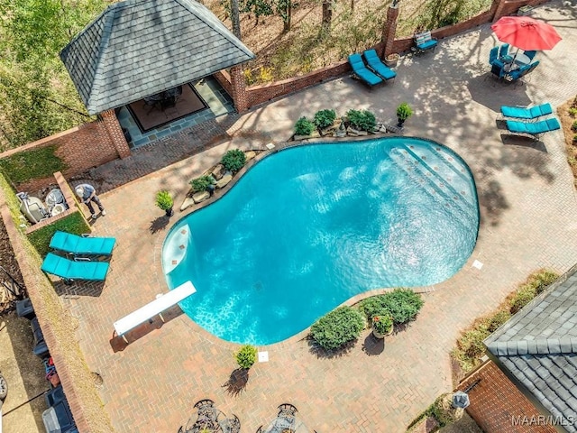 outdoor pool with a diving board, an exterior structure, an outdoor structure, and a patio