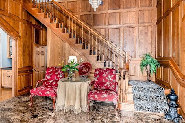 interior space with stairs, wooden walls, and a decorative wall