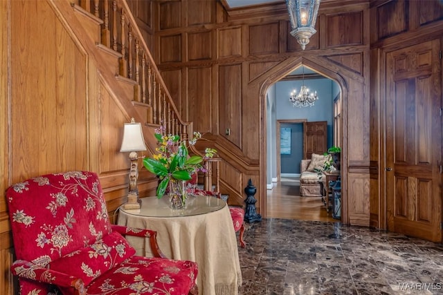 interior space featuring arched walkways, stairway, a chandelier, and wooden walls