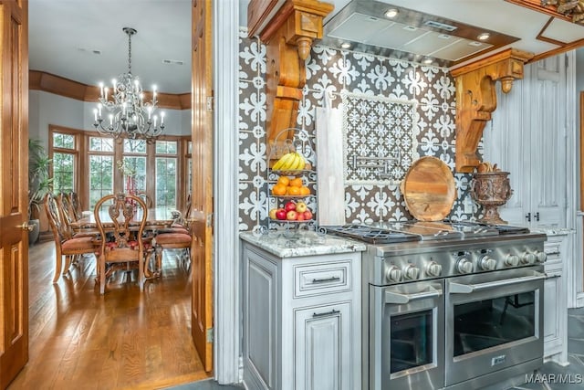 bar featuring visible vents, wood finished floors, range hood, double oven range, and a notable chandelier