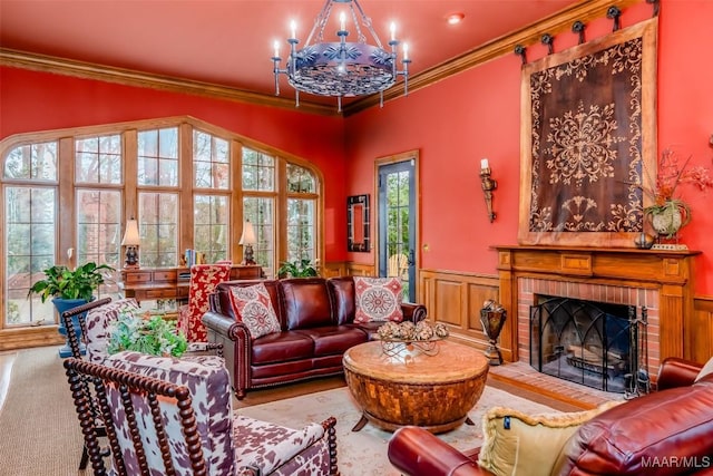 living area featuring a brick fireplace, ornamental molding, an inviting chandelier, and wainscoting