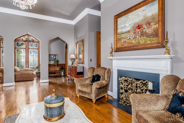 sitting room with a fireplace, a chandelier, crown molding, and wood finished floors