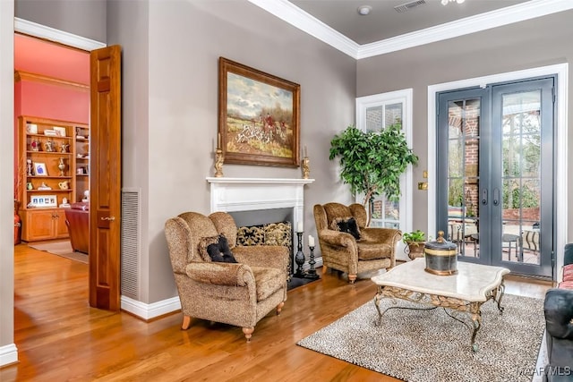 living area featuring ornamental molding, visible vents, a fireplace, and wood finished floors