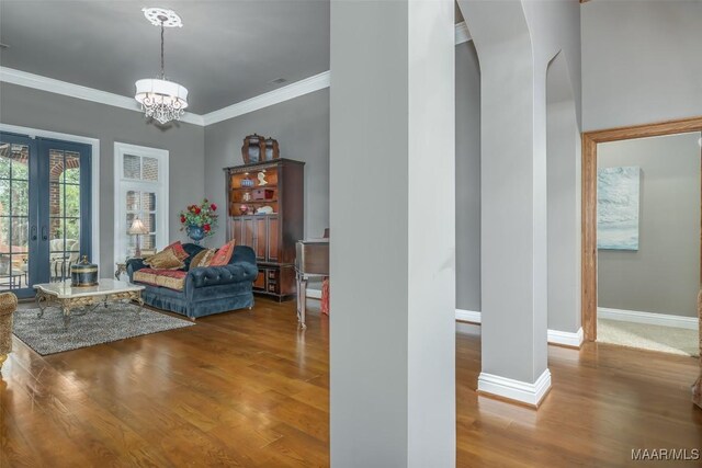 living room with crown molding, baseboards, a chandelier, and wood finished floors