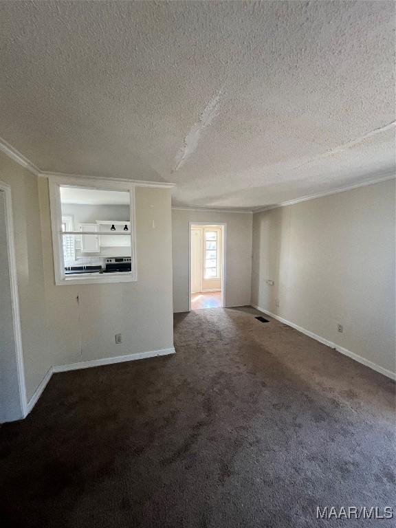 empty room with a textured ceiling, baseboards, and carpet flooring