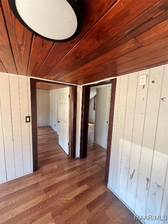 corridor featuring wood finished floors, wood ceiling, and wooden walls