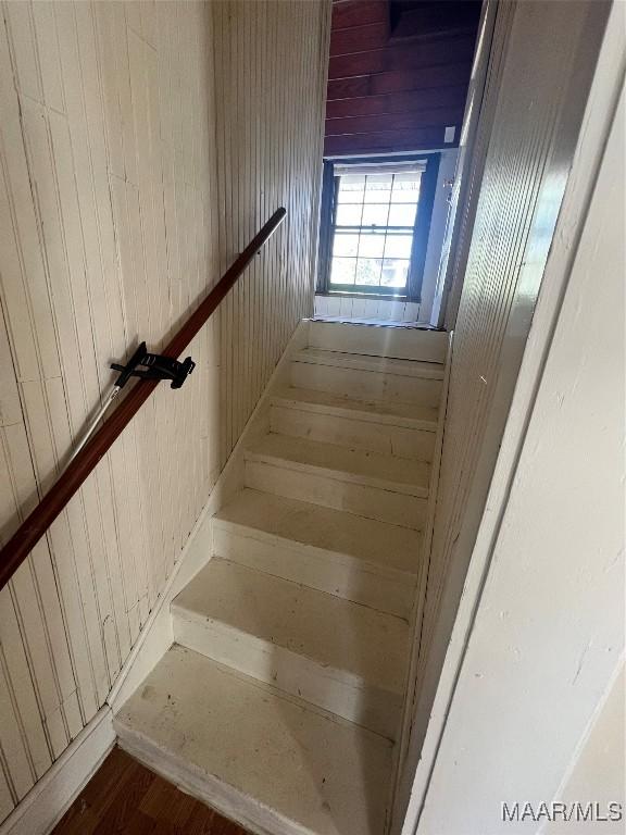 staircase featuring wooden walls and wood finished floors