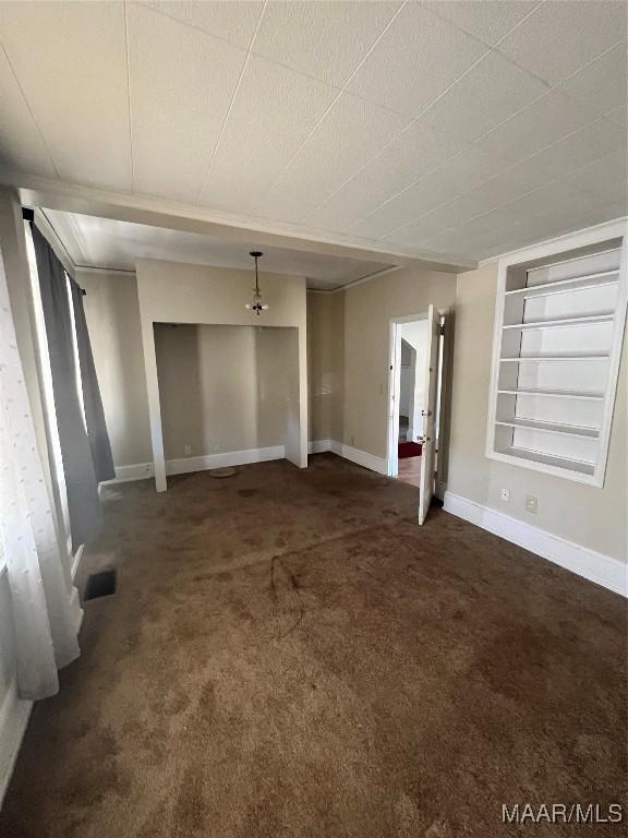 unfurnished living room with built in shelves, baseboards, and dark colored carpet