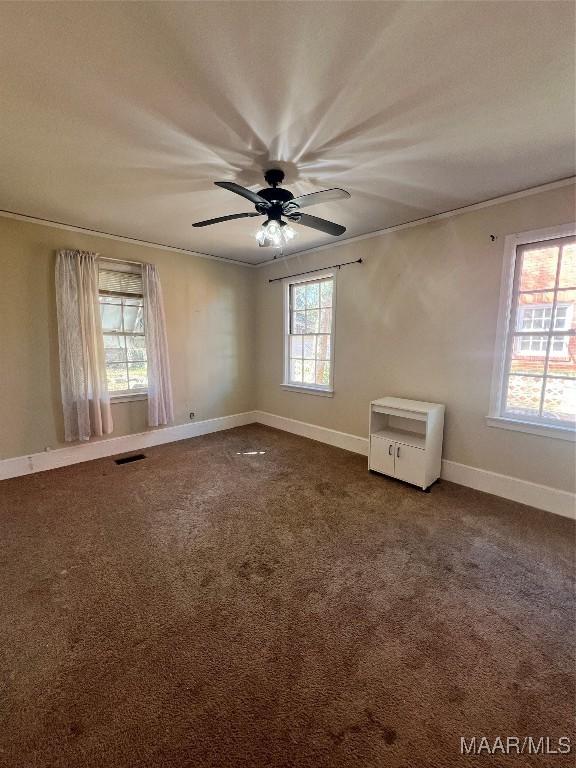 unfurnished room with dark colored carpet, a ceiling fan, visible vents, and baseboards