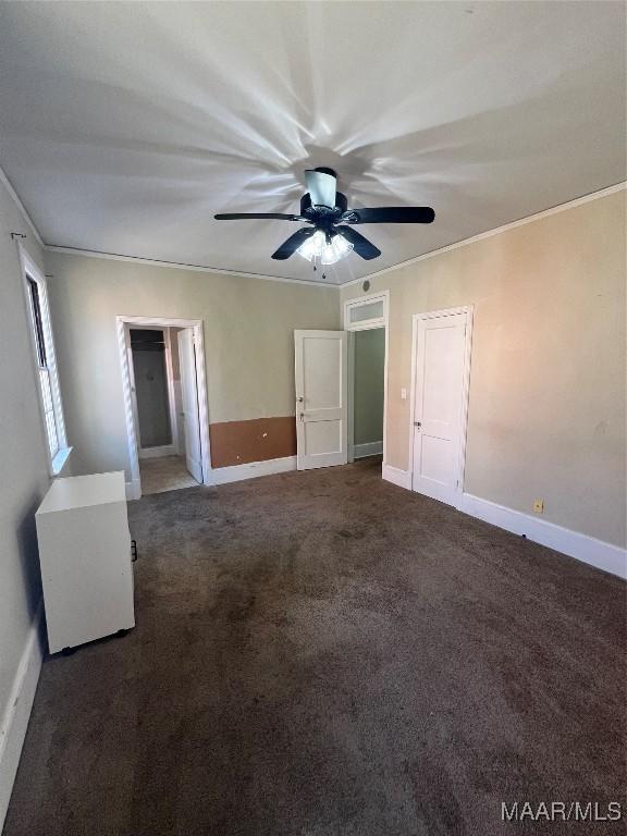 unfurnished bedroom featuring carpet floors, ornamental molding, baseboards, and ceiling fan