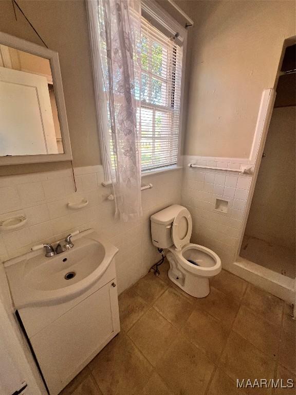 full bathroom with vanity, wainscoting, a shower stall, and toilet