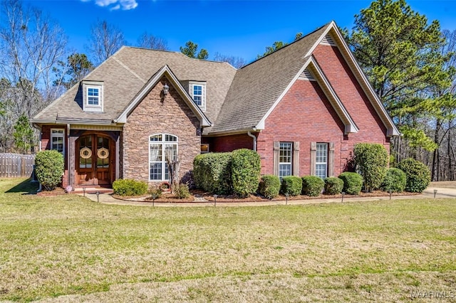 view of front of home featuring fence, a shingled roof, a front lawn, stone siding, and brick siding