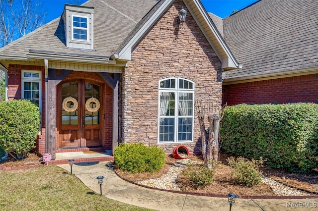 entrance to property with stone siding, brick siding, and roof with shingles