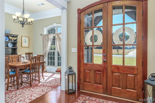 foyer with visible vents, dark wood finished floors, ornamental molding, french doors, and a chandelier