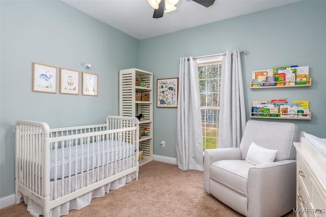 bedroom featuring baseboards, a crib, carpet, and ceiling fan