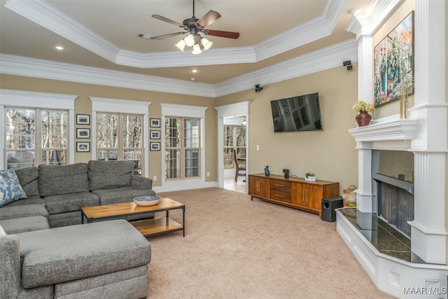 living area featuring a fireplace with raised hearth, crown molding, a tray ceiling, and carpet floors