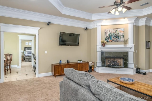 living room featuring baseboards, visible vents, ornamental molding, a tile fireplace, and light carpet