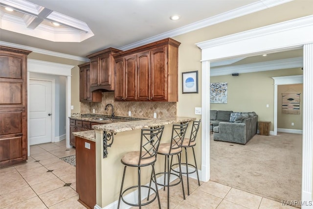 kitchen with light carpet, a breakfast bar, a sink, crown molding, and decorative backsplash