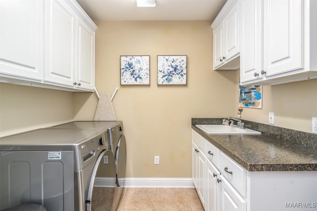 washroom with baseboards, light tile patterned flooring, cabinet space, a sink, and washing machine and dryer