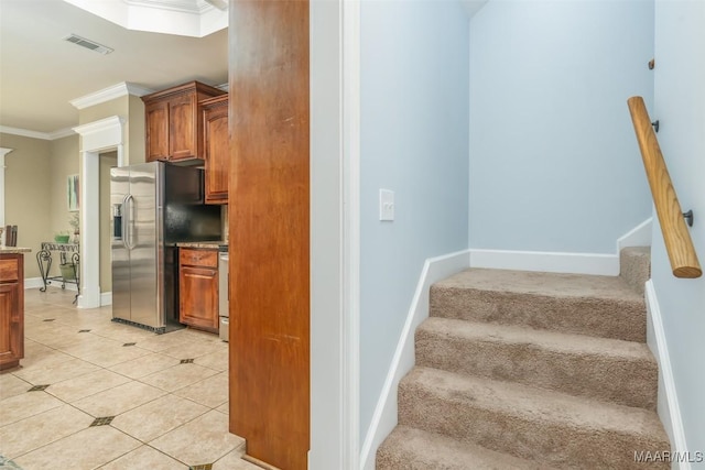 stairs featuring tile patterned floors, baseboards, visible vents, and ornamental molding