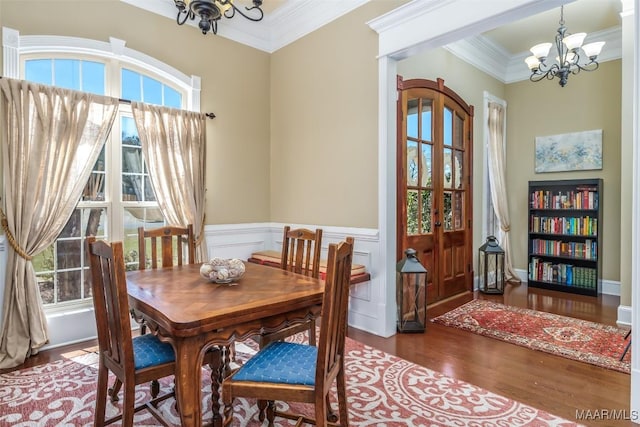 dining area with a notable chandelier, wainscoting, wood finished floors, and ornamental molding