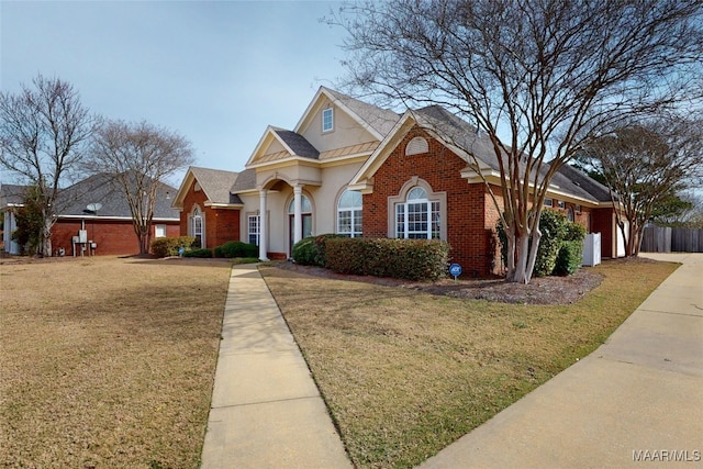 traditional-style home featuring a front lawn, brick siding, and stucco siding