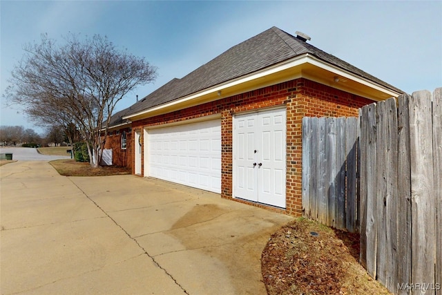 garage featuring concrete driveway and fence