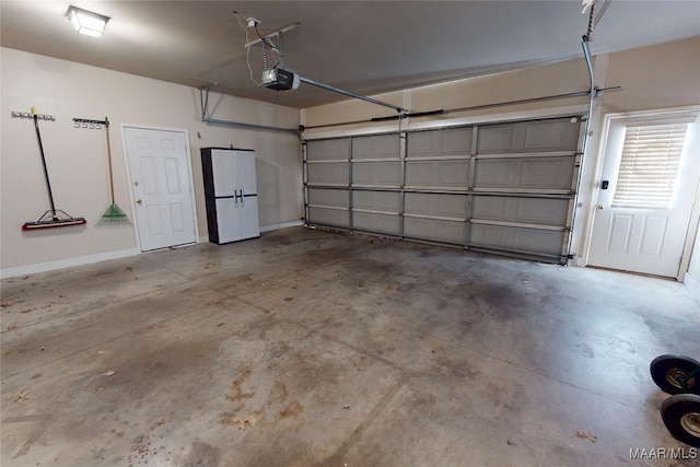 garage with freestanding refrigerator, a garage door opener, and baseboards