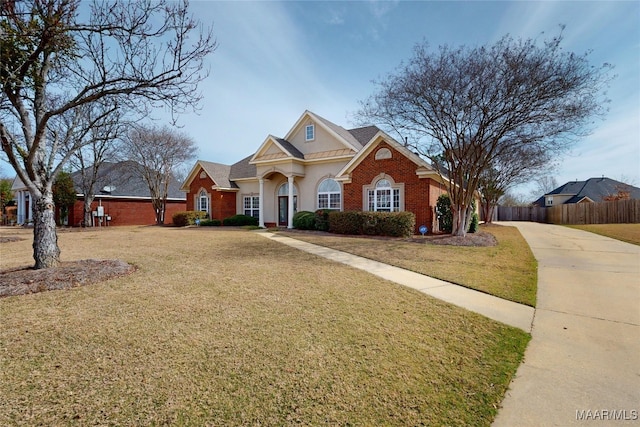 view of front facade with a front lawn, fence, brick siding, and driveway