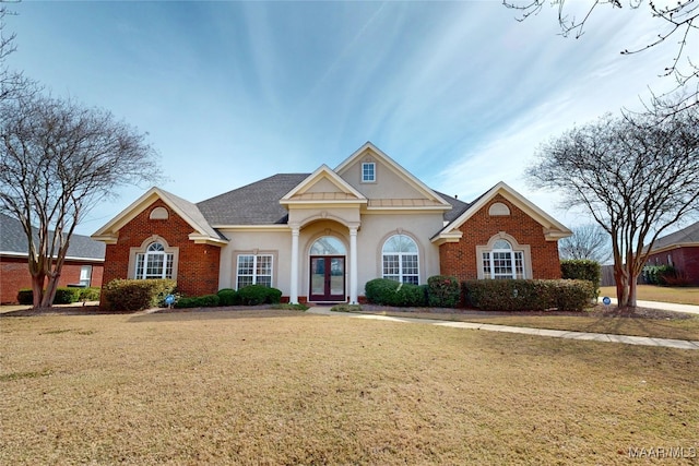 view of front of house with brick siding, french doors, and a front yard