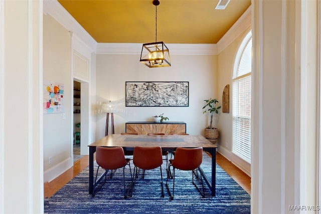 dining room featuring visible vents, a notable chandelier, ornamental molding, wood finished floors, and baseboards