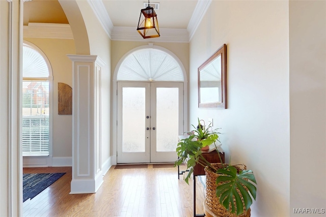 foyer with visible vents, light wood finished floors, arched walkways, french doors, and crown molding