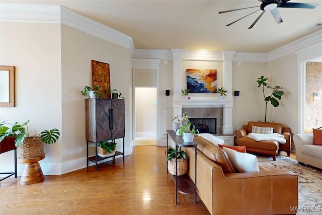 living area with crown molding, wood finished floors, visible vents, and a tile fireplace