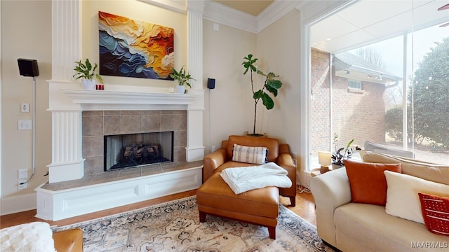 sitting room featuring wood finished floors, ornamental molding, and a tile fireplace