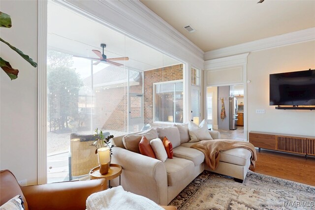 living room with ceiling fan, light wood-style flooring, visible vents, and ornamental molding