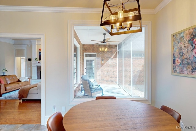 dining space with ceiling fan with notable chandelier, a tile fireplace, and crown molding