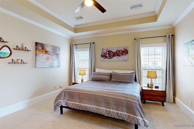 bedroom with a tray ceiling, multiple windows, light colored carpet, and visible vents