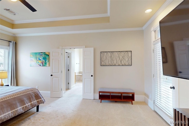 bedroom featuring baseboards, visible vents, a tray ceiling, light carpet, and crown molding