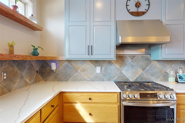 kitchen with stainless steel range with gas cooktop, light stone counters, decorative backsplash, wall chimney exhaust hood, and open shelves