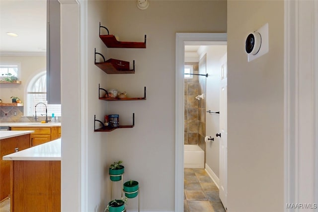 hall featuring ornamental molding, baseboards, and a sink